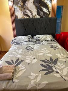 a bedroom with a bed with a bedspread with leaves at Hostal La Huerta in Huánuco