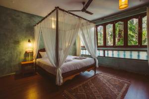 a bedroom with a canopy bed in a room with windows at Goa Yoga Retreat in Mandrem +23 photos