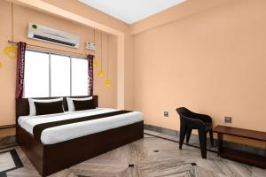 a bedroom with a bed and a chair and a window at Hotel O Aarshi Palace in Cuttack