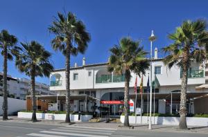 a building with palm trees in front of a street at SOL by Meliá Los Fenicios in La Herradura