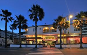 a building with palm trees in front of it at SOL by Meliá Los Fenicios in La Herradura