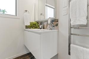 a white bathroom with a sink and a mirror at Sheena Apartment in Manila