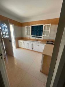 a large kitchen with white cabinets and a window at maison de charme in Fafou