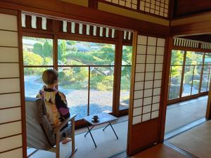 a child sitting in a chair looking out of a window at 茶室山谷庵 in Gero +5 photos