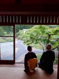 two men sitting on a window looking out at a garden at 茶室山谷庵 in Gero