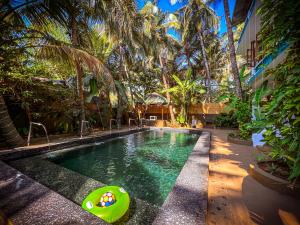 a swimming pool in a resort with palm trees at Goa Yoga Retreat in Mandrem