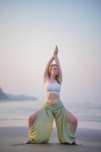 a woman doing a yoga pose on the beach at Goa Yoga Retreat in Mandrem