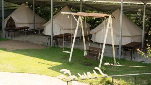 a group of tents with chairs and a swing at Yangyang Slowstay Pension in Yangyang