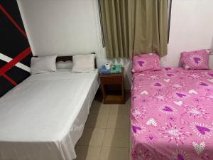 two beds in a room with pink sheets at Hospedaje Lima Suite in Piura