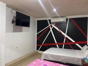 a room with a bed and a tv on the wall at Hospedaje Lima Suite in Piura