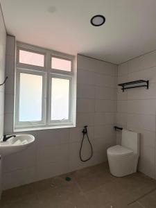 a bathroom with a toilet and a sink and a window at Hotel & Recreation Apsara Bukit Residen in Kuala Lipis