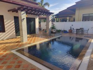 a swimming pool in front of a house at Nana's Bar & Hotel in Nong Prue
