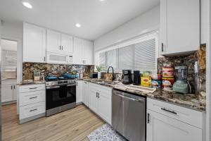 a white kitchen with white cabinets and appliances at Entire Private House with King Bed, 80 TV, Gated Yard, Ranch Style, 4 Bedrooms 2 Bathrooms, Available Now in El Cajon