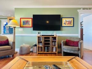 a living room with two chairs and a flat screen tv at Clamelot in Holden Beach