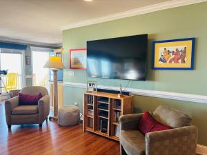 a living room with two chairs and a flat screen tv at Clamelot in Holden Beach