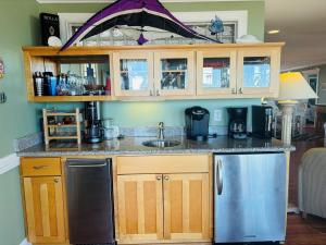 a kitchen with a counter with a sink and a refrigerator at Clamelot in Holden Beach +54 photos