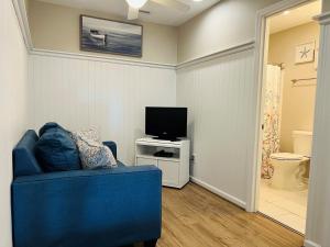 a living room with a blue couch and a television at Avalon East-Duplex in Holden Beach