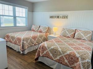 a bedroom with two beds and a sign on the wall at Avalon East-Duplex in Holden Beach +65 photos