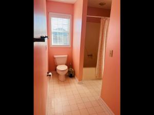a bathroom with a toilet and a window at Victoria in Holden Beach