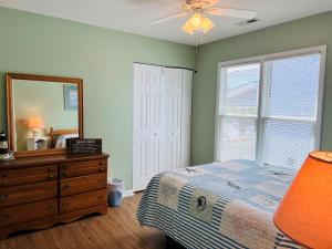 a bedroom with a bed and a dresser and a mirror at Tradewinds in Holden Beach +31 photos