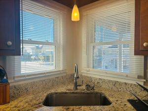 a kitchen with a sink and two windows at Plan Beach home in Holden Beach