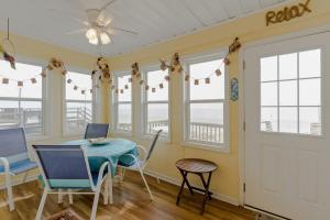 a dining room with a table and chairs and windows at Yellow Bird in Holden Beach