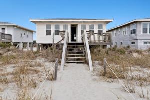 a house on the beach with stairs to the sand at Yellow Bird in Holden Beach +10 photos