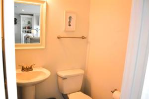 a bathroom with a sink and a toilet and a mirror at Nautilus Home in Holden Beach