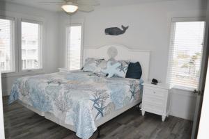 a bedroom with a bed with a blue and white comforter at Nautilus Home in Holden Beach
