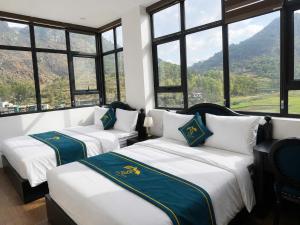 two beds in a room with large windows at Son Tinh Hotel in Dồng Văn +55 photos