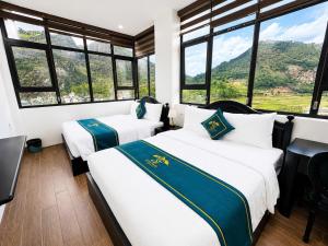 two beds in a room with large windows at Son Tinh Hotel in Dồng Văn