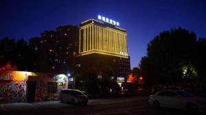 two cars parked in front of a tall building at night at Harbin Splendent Hotel in Shuangcheng