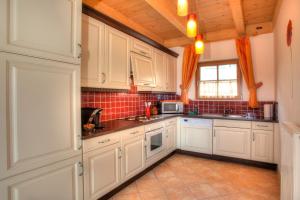 uma cozinha com armários brancos e piso em azulejo em Mathiasl Wellness-Ferienhäuser em Bodensdorf