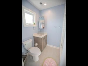 a bathroom with a toilet and a sink and a mirror at Three Girls in Holden Beach