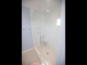 a shower with a glass door in a bathroom at Three Girls in Holden Beach