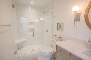 a white bathroom with a shower and a toilet at Three Girls in Holden Beach