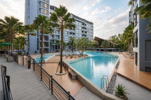a swimming pool with palm trees and a building at Oasis in CityGate 1BR Suite in Kamala Beach