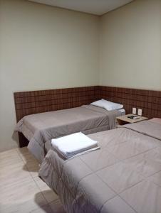 a room with two beds and a table at Hotel Central Cardinal Pedro Juan Caballero in Pedro Juan Caballero