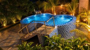 a swimming pool in a backyard at night at Happy Mates Forest Villa in Pondicherry