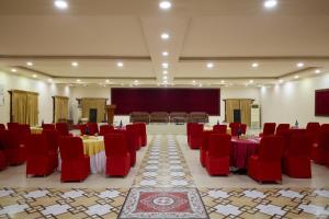 a banquet hall with red chairs and tables and a screen at Mithila Yatri Niwas in Janakpur
