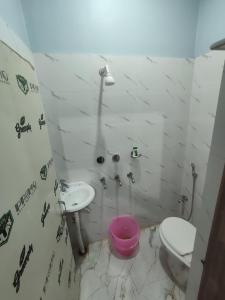 a bathroom with a toilet and a sink and a pink bucket at Hotel Namaste Katihar INN in Katihār