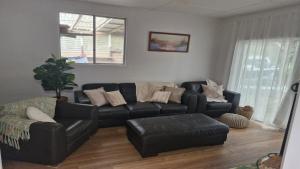a living room with a black leather couch and chair at Beachside Bungalow in Minnie Water