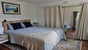 a bedroom with a bed with a blanket on it at Beachside Bungalow in Minnie Water