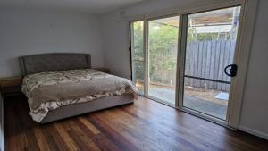 a bedroom with a bed and a sliding glass door at Beachside Bungalow in Minnie Water