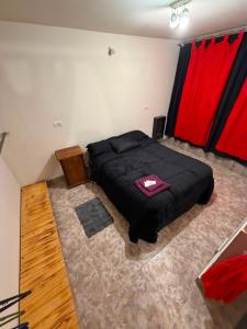a bedroom with a black bed and red curtains at La Cumbre in Chos Malal