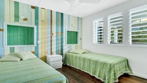 two beds in a room with two windows at Moomba On Main in Wooli