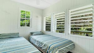 two beds in a room with white walls and windows at Moomba On Main in Wooli
