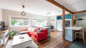 a living room with a red couch and a kitchen at Wooli House in Wooli