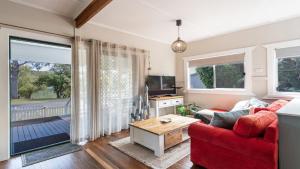 a living room with a red couch and a table at Wooli House in Wooli +12 photos