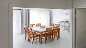 a dining room with a table and wooden chairs at Twin Palms Retreat in Wooli